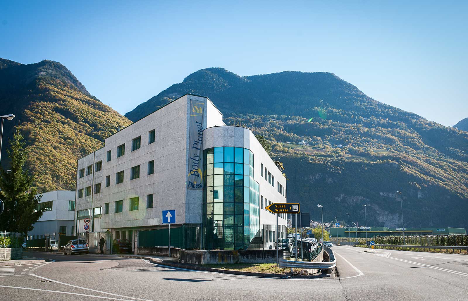 Blick auf das Gebäude in Leifers bei Bozen  mit zahlreichen Glasfenstern, in dem sich das Fitnessstudio Body Planet befindet.